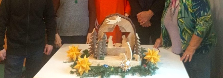 Menschen um eine Holzkrippe